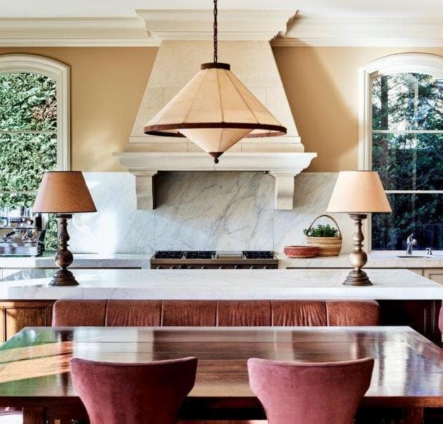 Elegant kitchen with marble island, conical pendant light, and dining table with pink chairs.